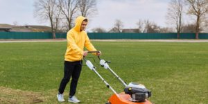 Young Man Trimming Grass in the Garden